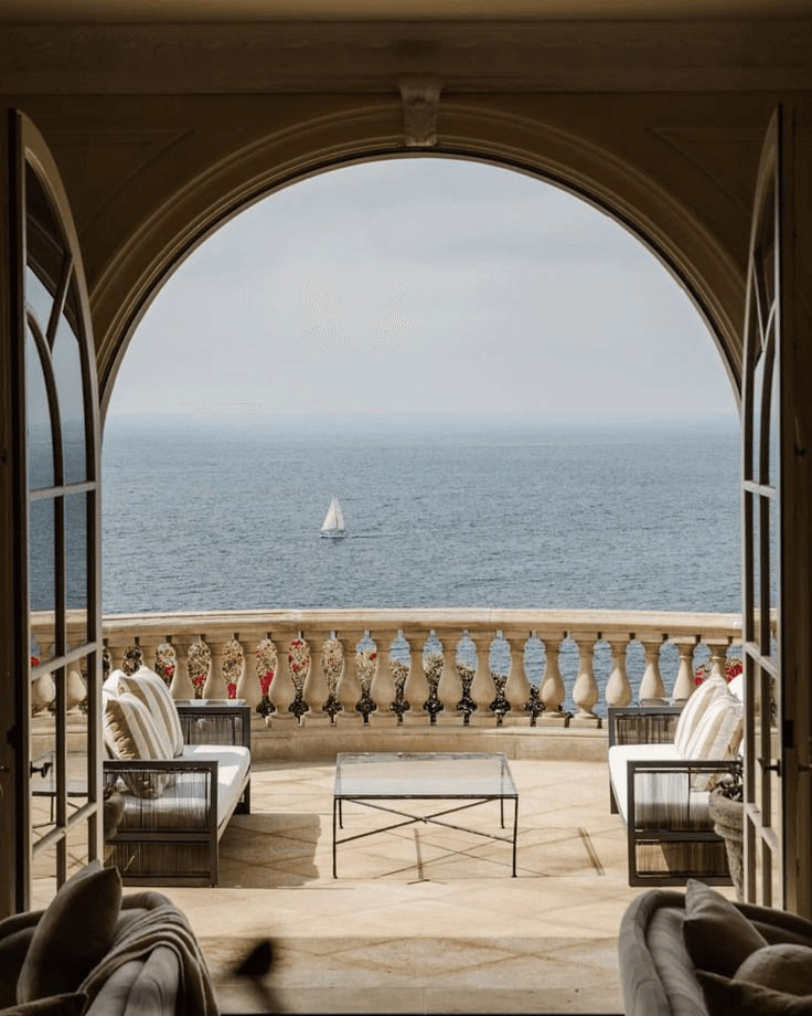 A sea view framed by an arched window from a private terrace